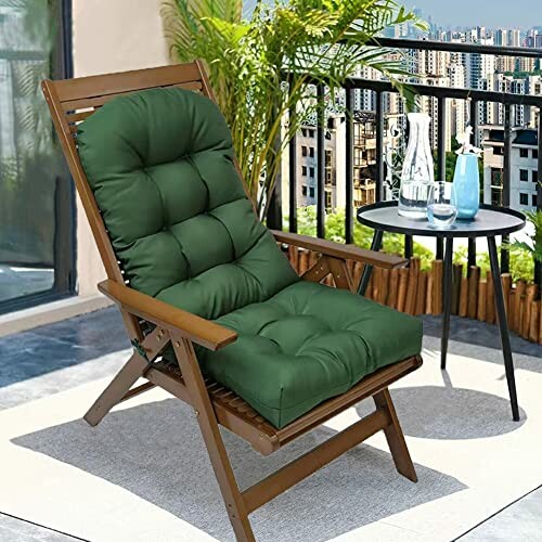 Wooden chair with green cushion on balcony, city view in background.
