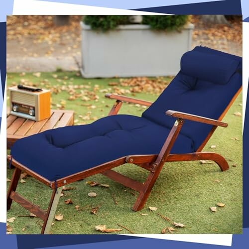 Wooden lounge chair with blue cushion next to a vintage radio on grass.