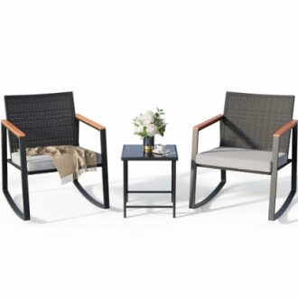 Outdoor rocking chair set with two chairs and a small table with flowers.