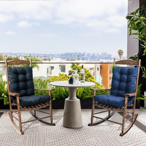 Two rocking chairs on a patio with a small table and city view