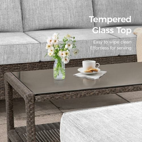 Wicker coffee table with tempered glass top, cup, and flowers.