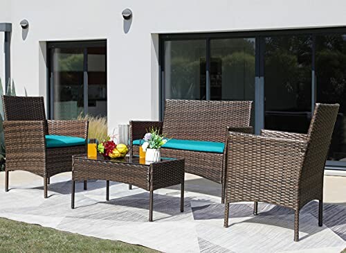Wicker patio furniture set with chairs, loveseat, and table in front of modern house.